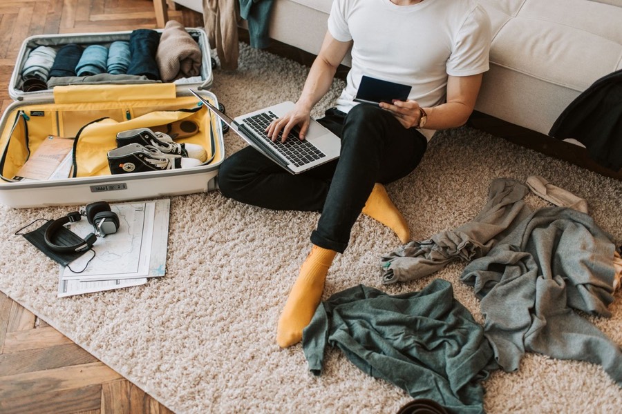 Pessoa organizando notebook, celular e mala na primeira semana de chegada a Brasília.