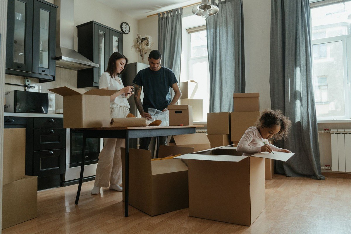 Família desempacotando caixas em apartamento novo durante a organização de uma mudança para Brasília.