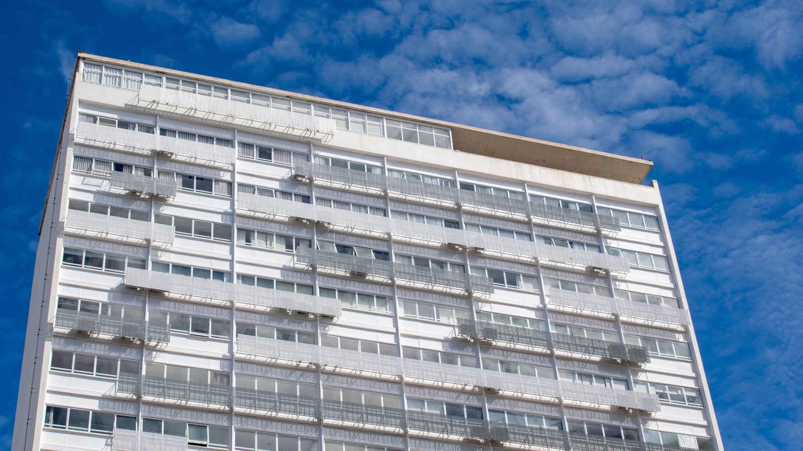 Prédio residencial moderno em Brasília sob céu azul.