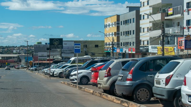 Rua comercial no Distrito Federal com carros estacionados ao longo da via.