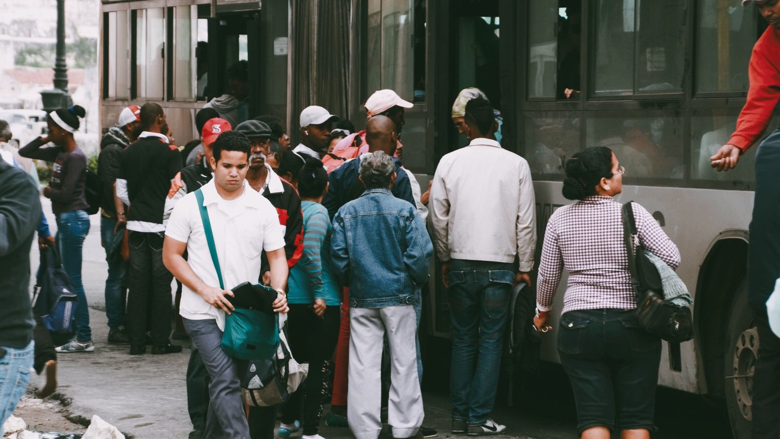 Fila de passageiros embarcando em um ônibus urbano em um ponto de parada.