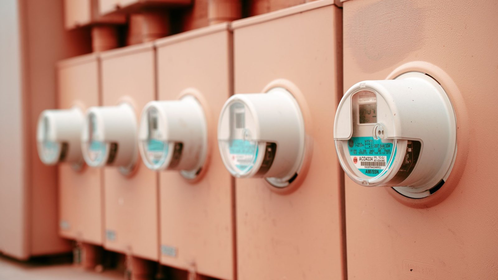 Fileira de medidores de energia elétrica instalados lado a lado em um painel.